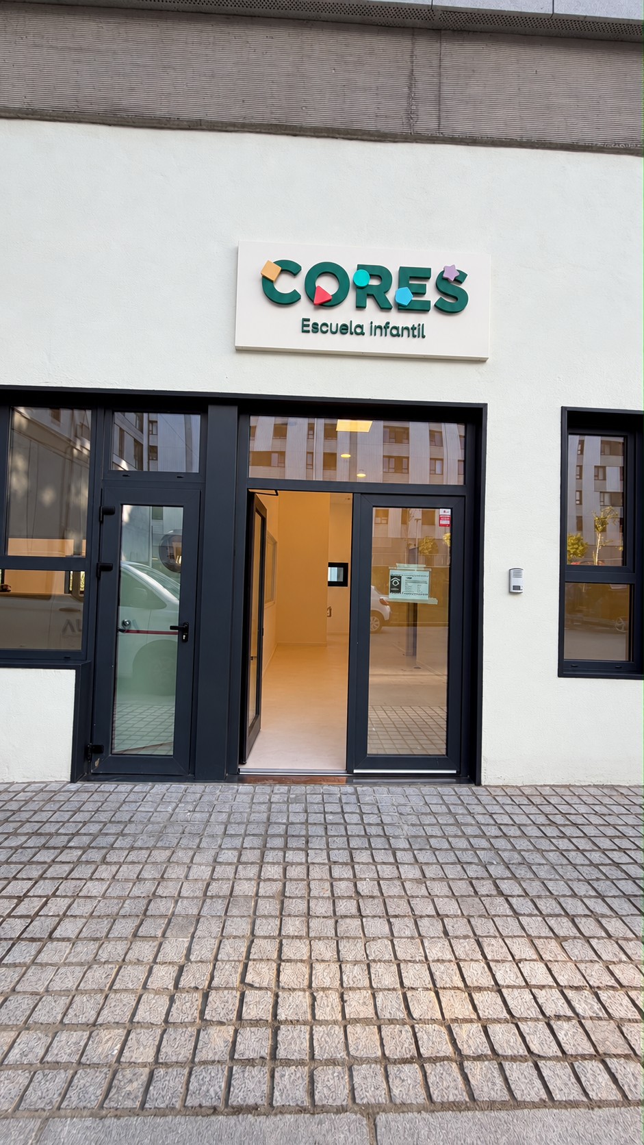 Entrada acristalada con rótulo de la Escuela Infantil Cores