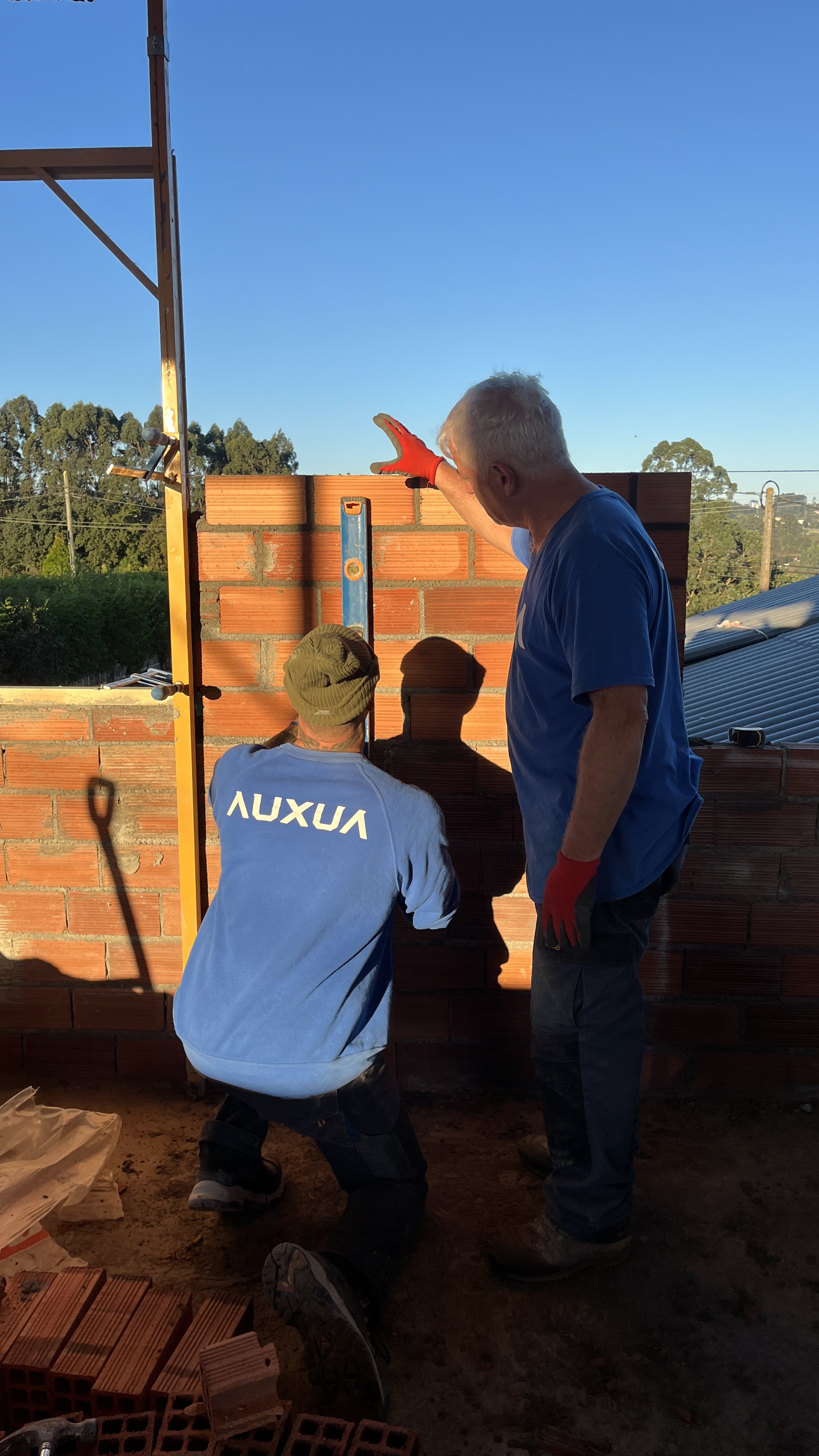 Dos profesionales de AUXUA levantando un cerramiento de ladrillo